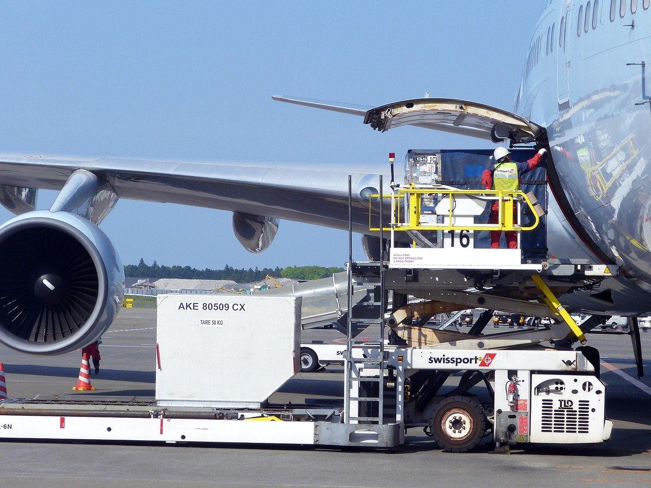 Professional cargo aircraft loading operations at modern airport terminal with ULD containers - Safe Fly Aviation cargo charter services from India