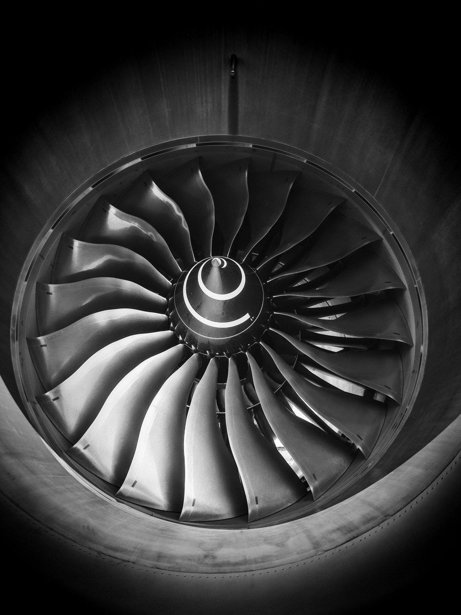 Close-up of modern turbofan engine fan section with titanium alloy blades, swept-back aerodynamic design, and nacelle intake lip