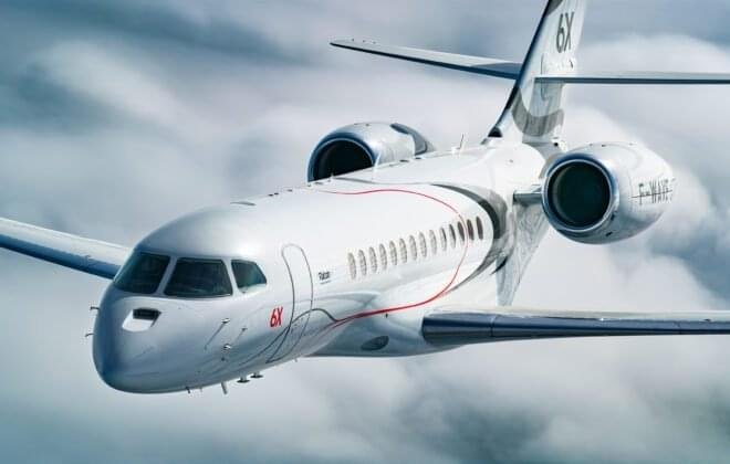 Falcon 6X private jet in flight over mountains at sunset